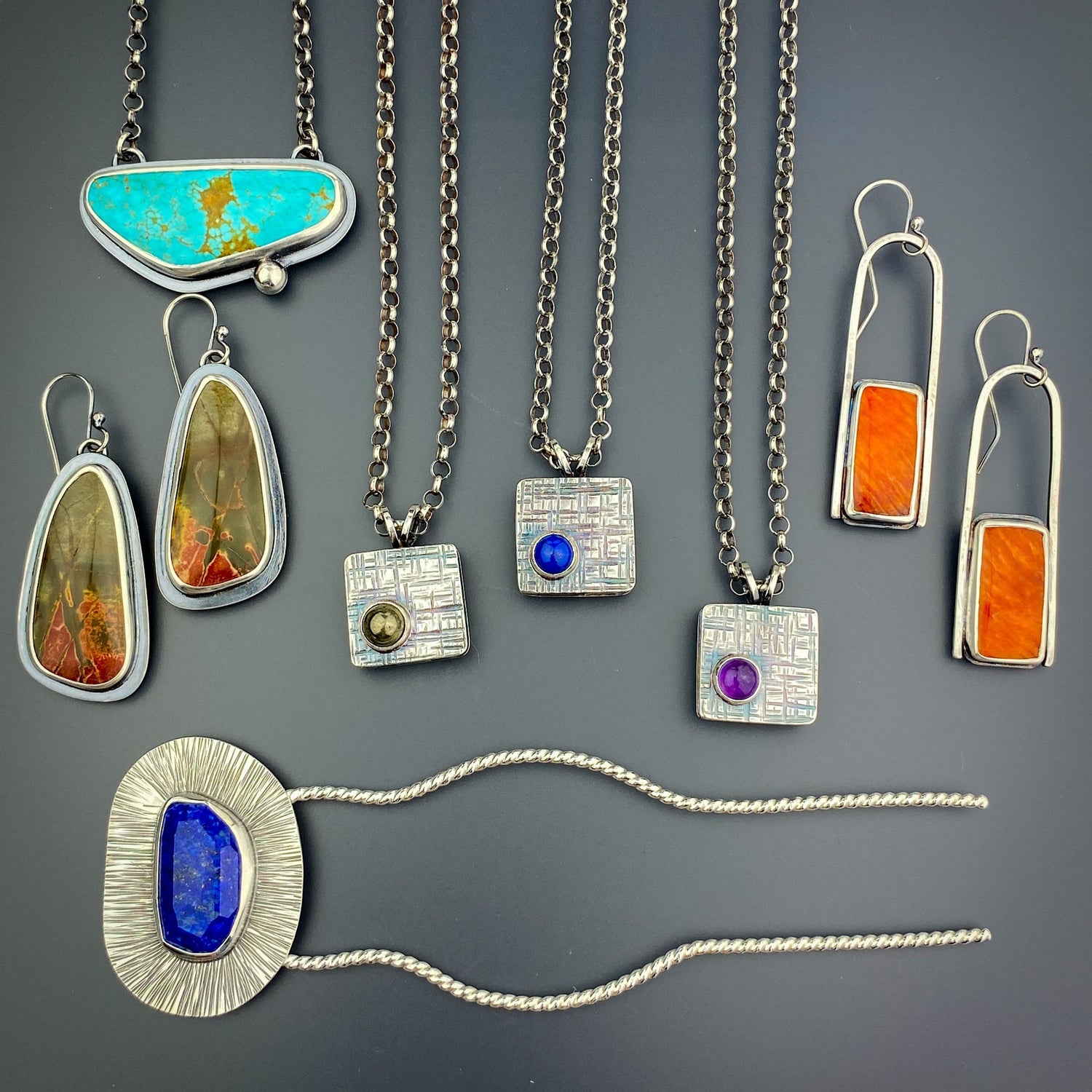 a group of silver jewelry. Earrings, necklaces, and a hair fork. Several stones in different colors are included.