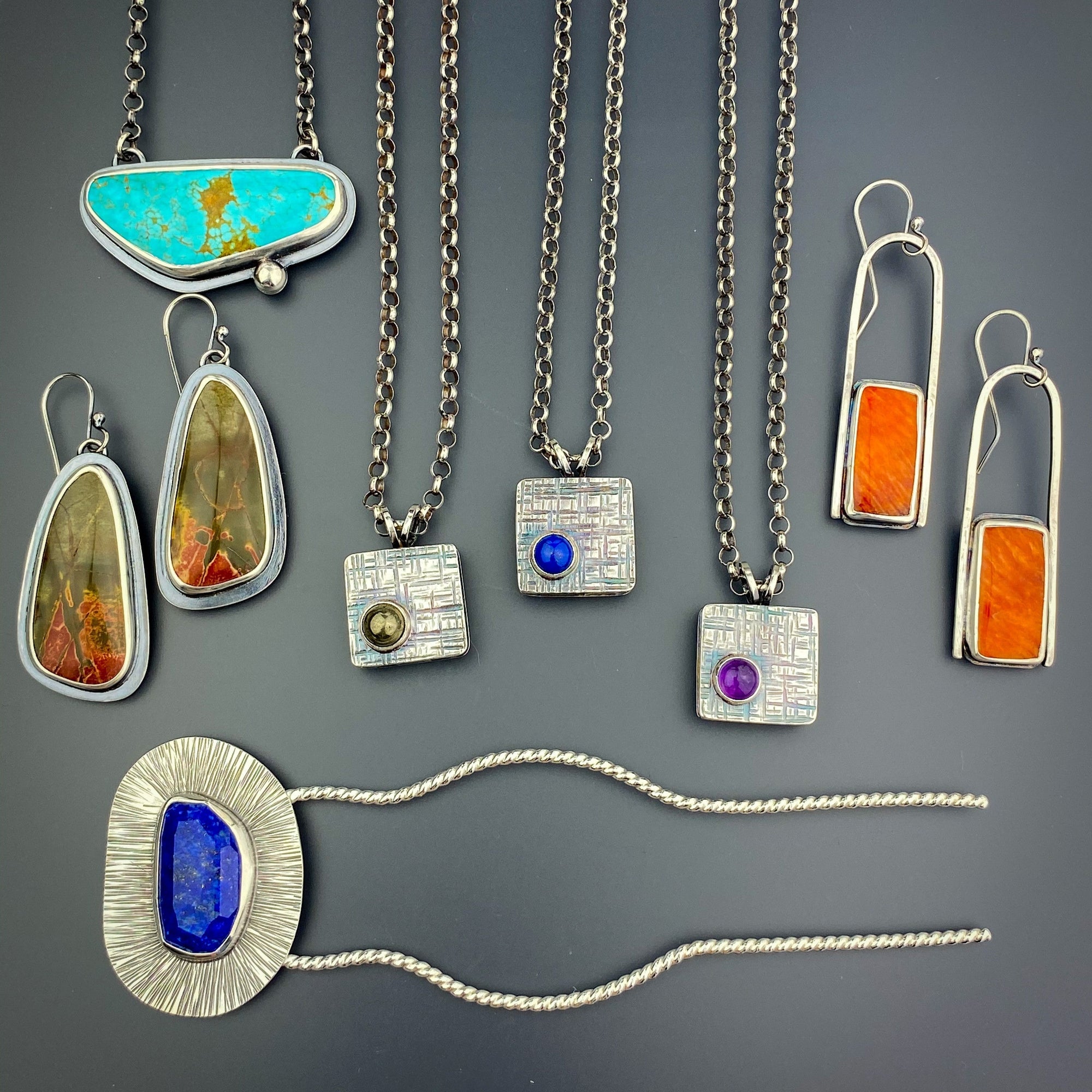 a group of silver jewelry. Earrings, necklaces, and a hair fork. Several stones in different colors are included.