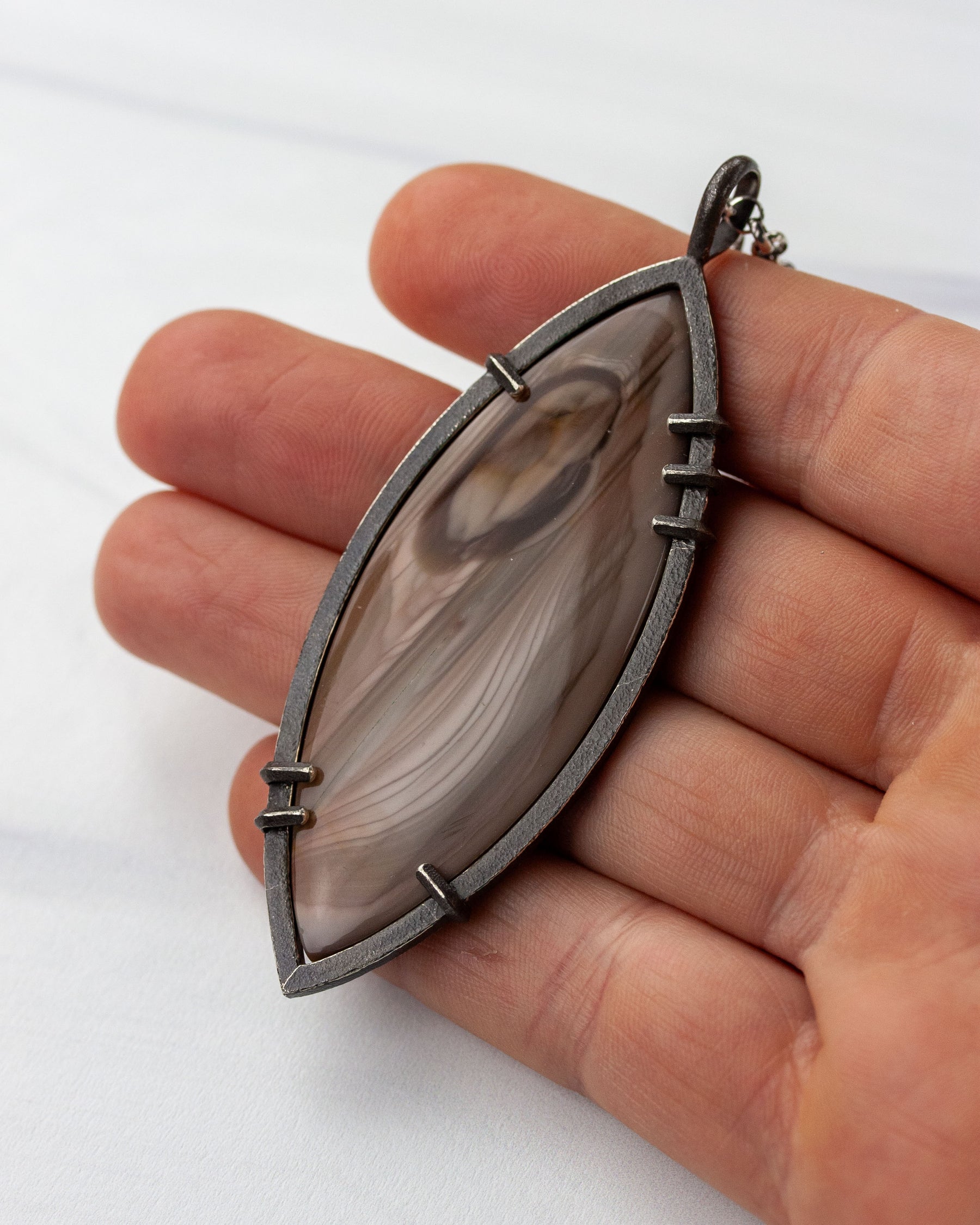 Hand holding Imperial jasper pendant in sterling silver for scale