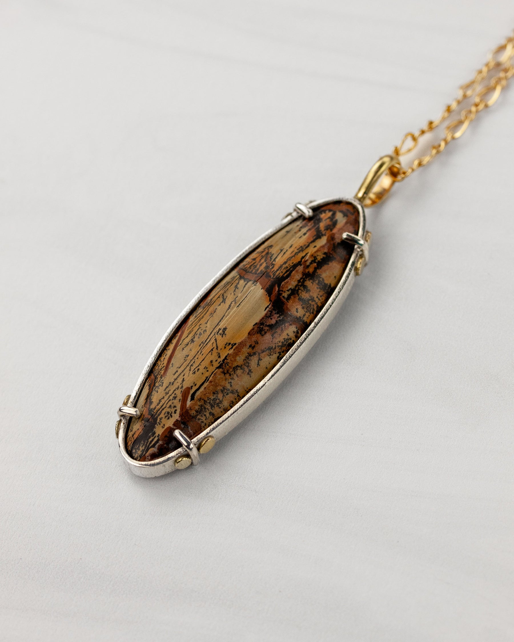 Indian paint stone pendant in silver and gold on white background