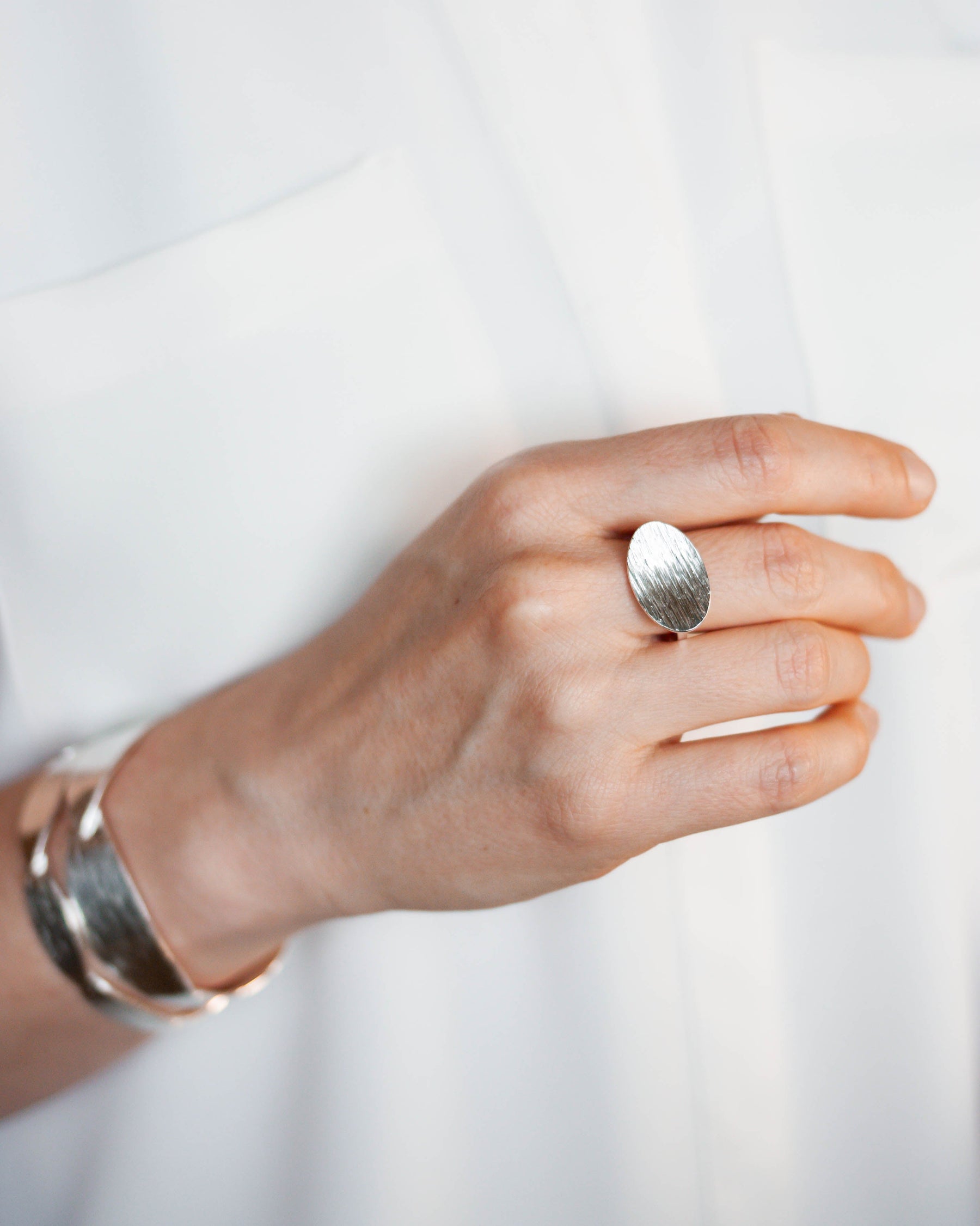 Hand wearing a silver ring on a white background. Sterling silver ring by houston-based jewelry artist Lindsey Johnson of Geophilia Studio.
