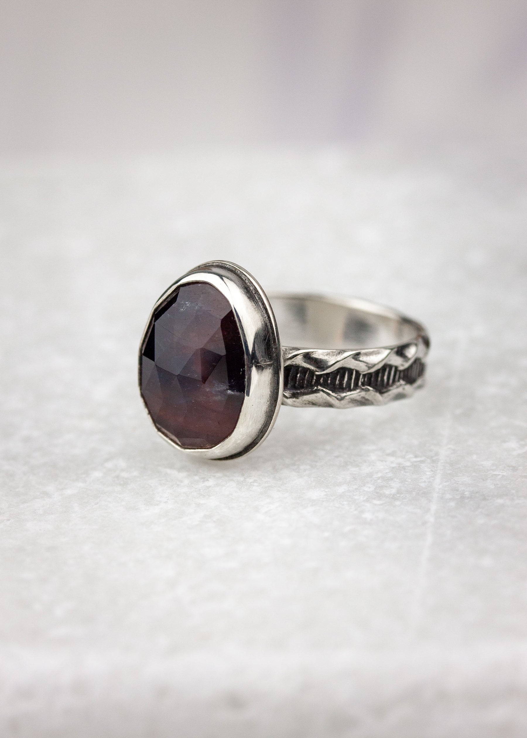 Purple sapphire ring displayed on white marble