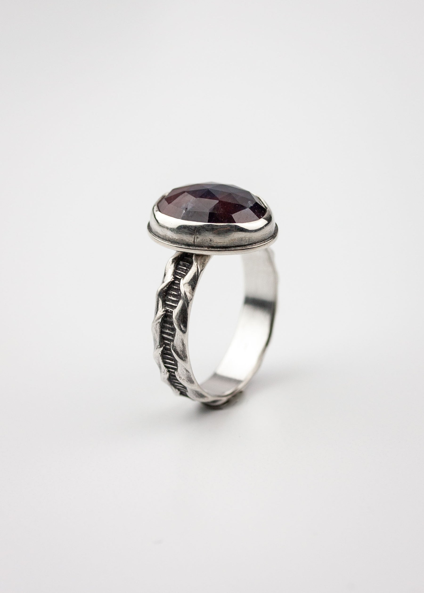 Maroon sapphire ring showing highly textured silver ring band