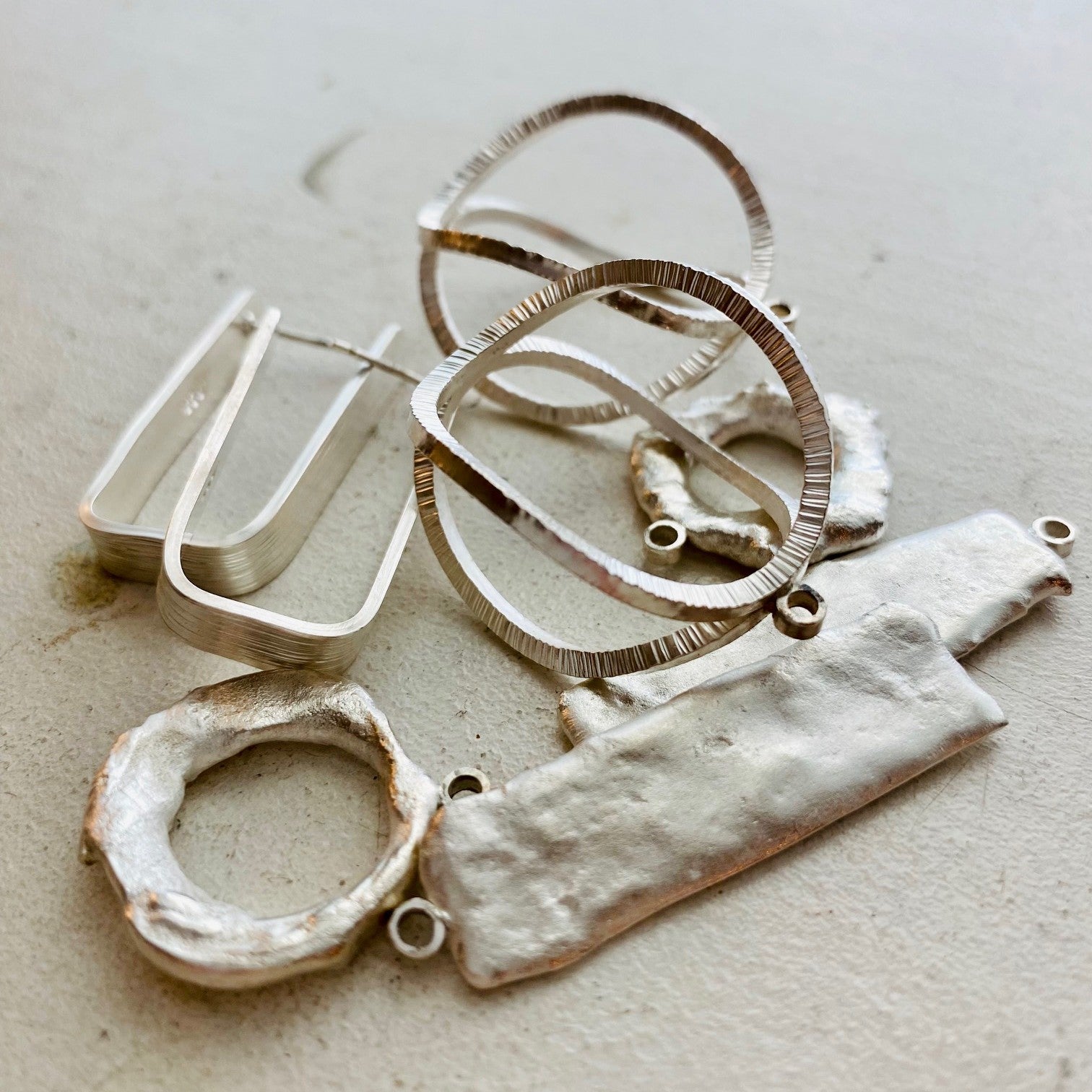 a jumble of in-process jewelry pieces on a white background