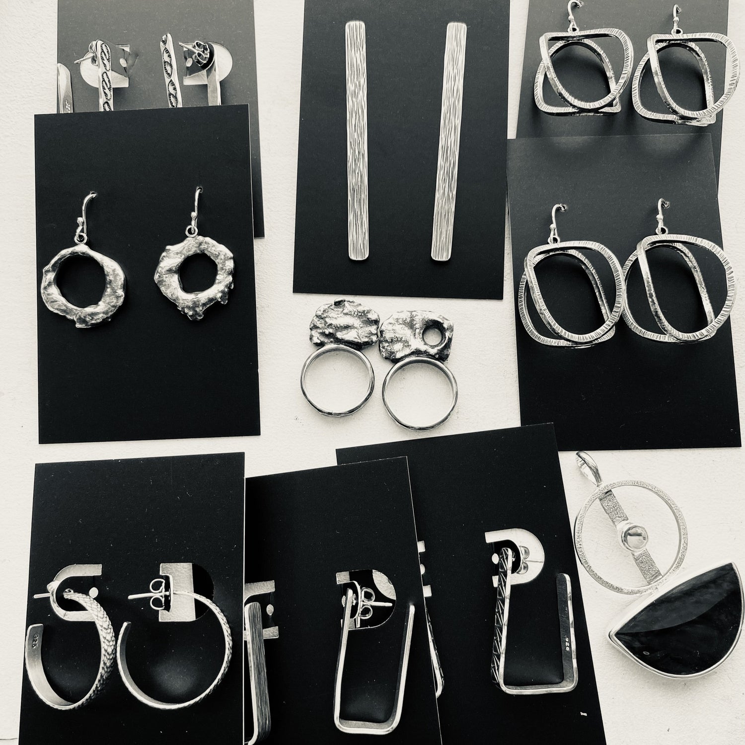 Black and white picture of silver jewelry on black paper jewelry cards