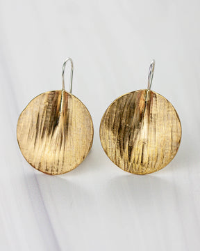 Golden bronze earrings on a white background. The shape is circular, lightly textured and folded to create a 3D effect.