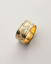 Golden brass ring with intricate patterns on a light gray background.