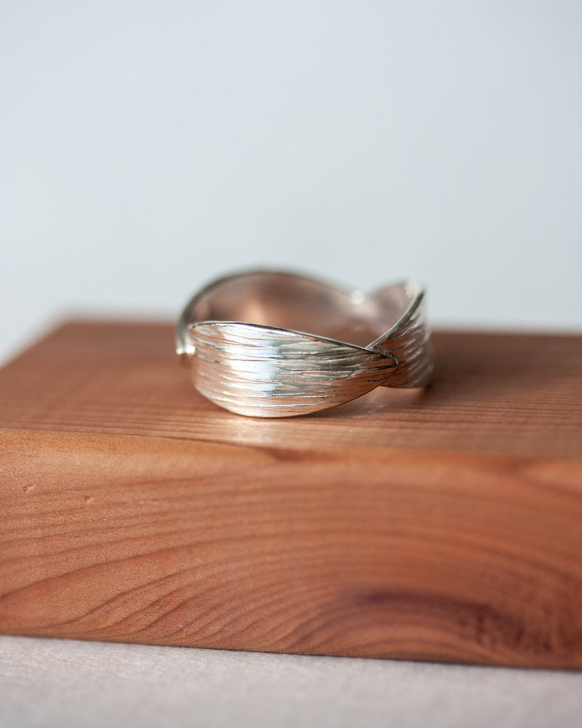 Silver ring on a wooden surface with a light gray background