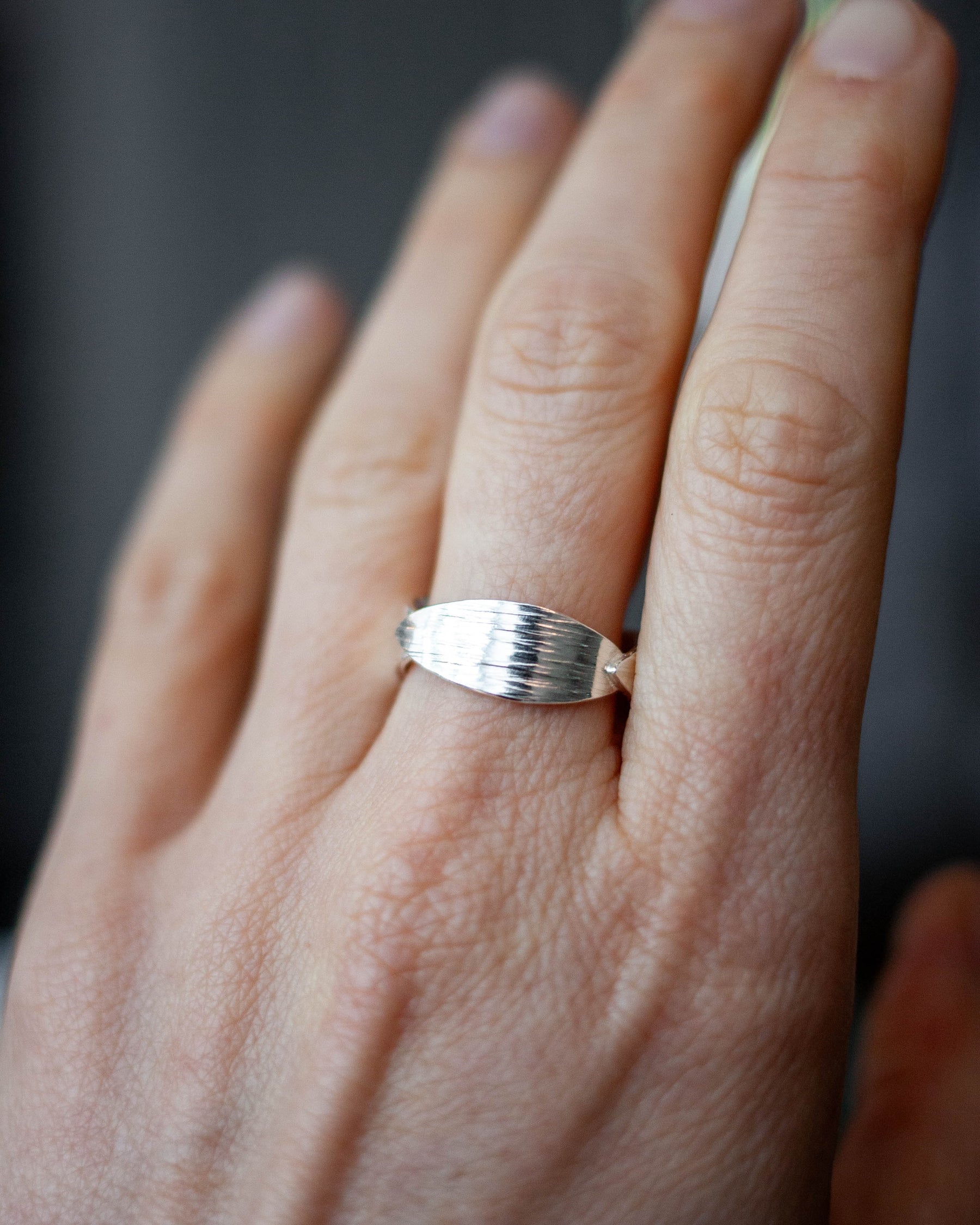 Silver ring on a person's finger with a blurred background