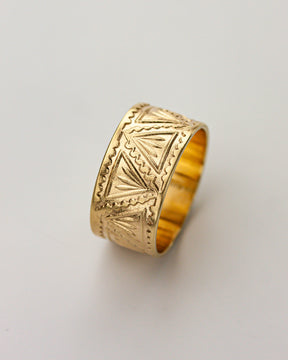 Golden brass ring with geometric patterns on a light gray background