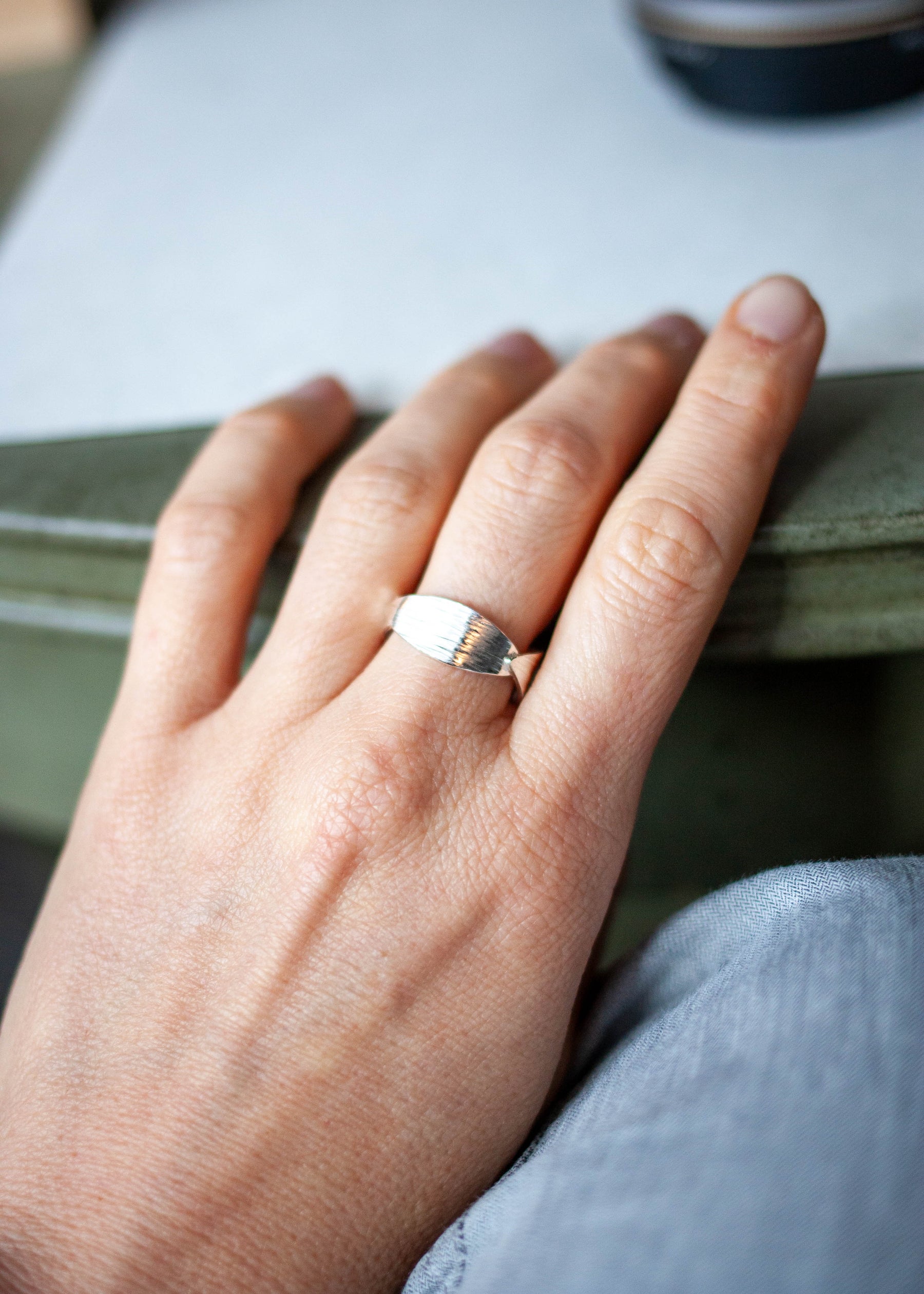 Hand wearing a ring with a blurred background