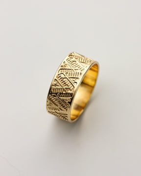 Golden brass ring with intricate patterns on a light gray background