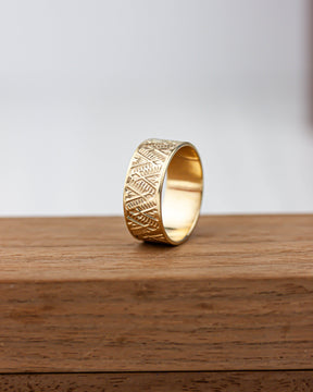 Golden brass ring with intricate patterns on a wooden surface