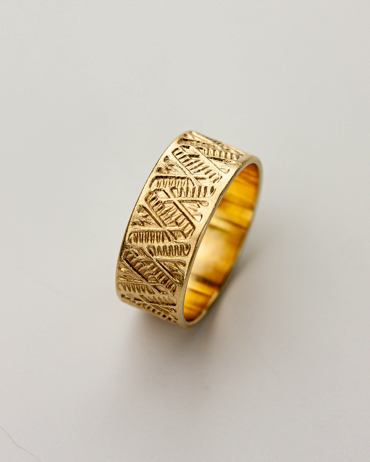 Golden brass ring with intricate patterns on a light gray background